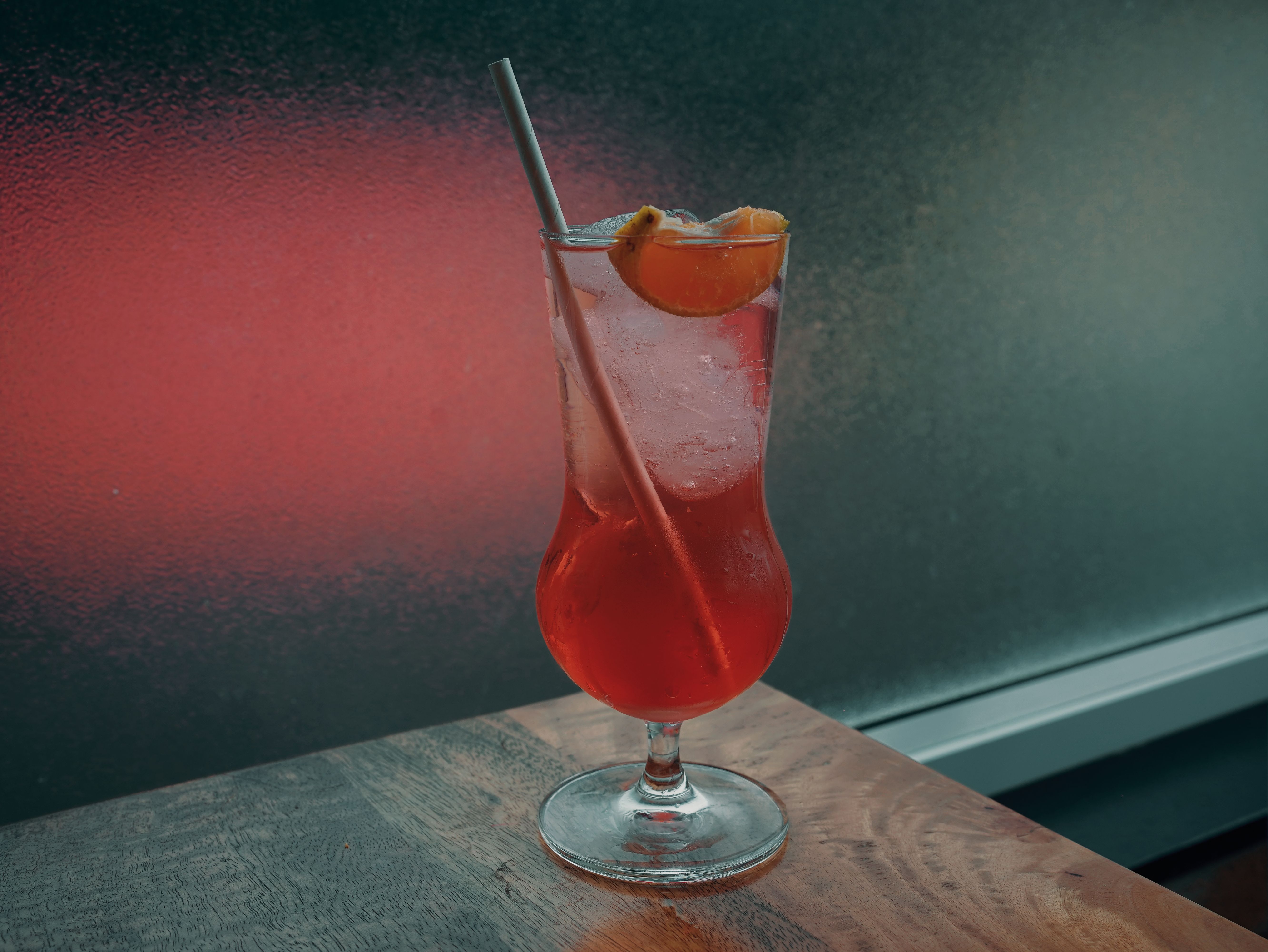 Unbranded red citrus drink in a stemmed glass on a wooden table