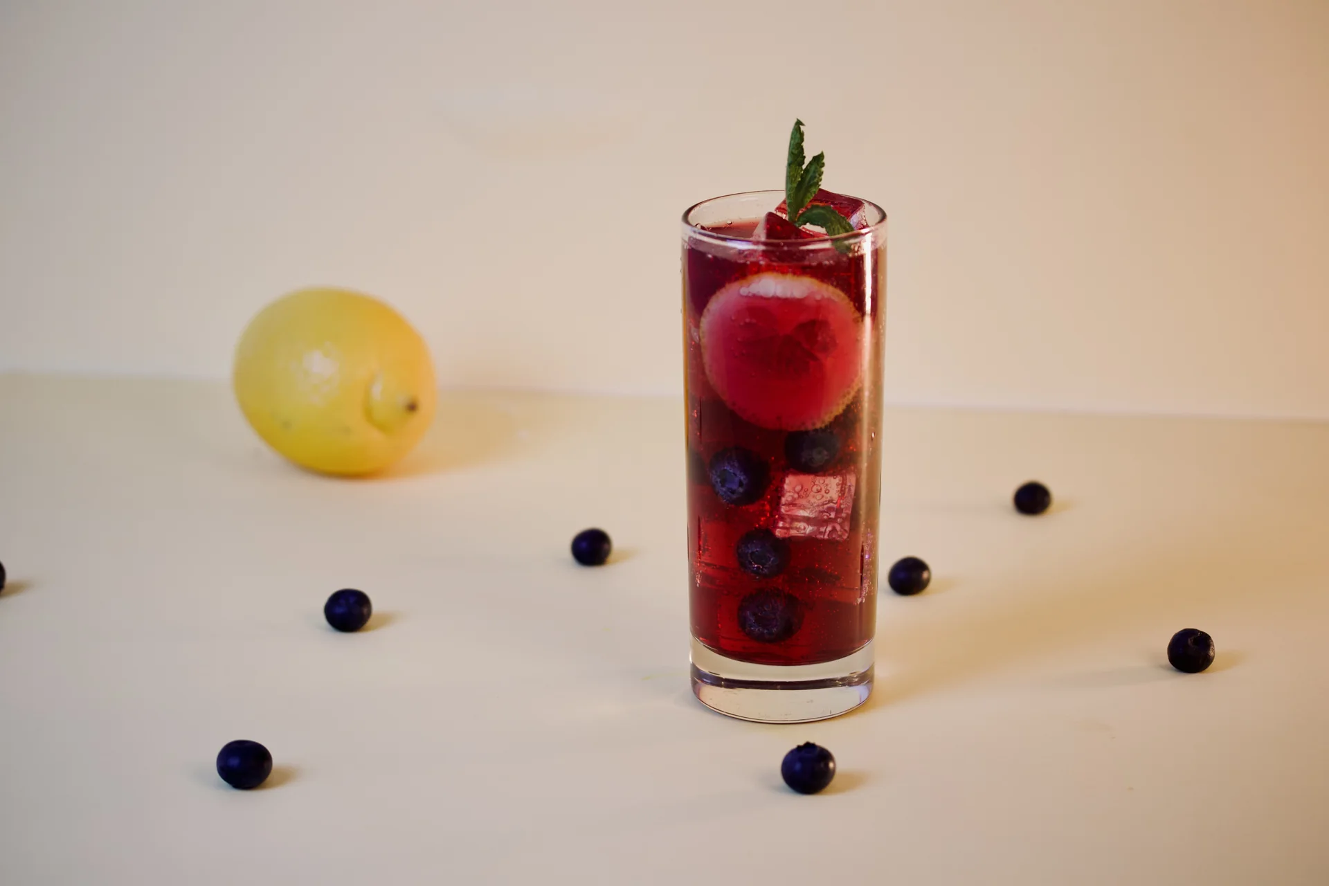 Berry-colored sparkling drink with lemon and blueberries